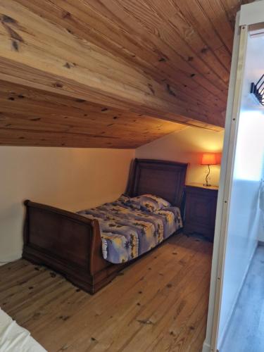 sypialnia z łóżkiem i drewnianym sufitem w obiekcie Loft ravissant avec parking gratuit sur place w mieście Lédat