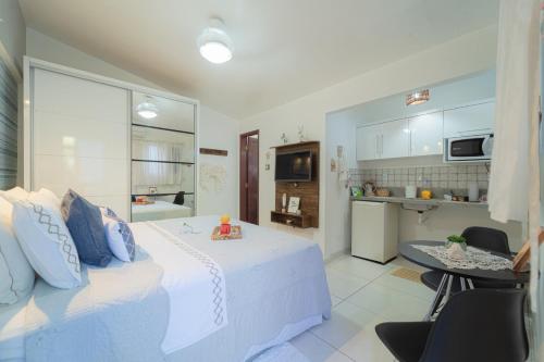 a bedroom with a white bed and a kitchen at Pousada Recanto da Família in Natal