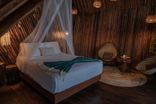 a bedroom with a bed with a mosquito net at Casa Hayhu in Mahahual