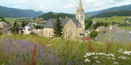a church on a hill with a field of flowers at Gîte La Grange in Méaudre