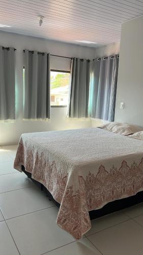 een slaapkamer met een bed en een raam met gordijnen bij KasaNivea in Pirenópolis