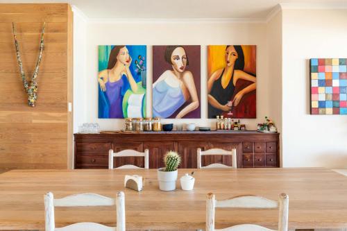 a dining room with paintings on the wall at Dune Beach House in Wilderness