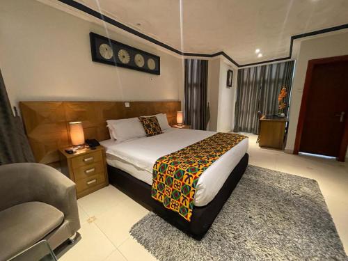 Airport West Hotel في آكرا: غرفة نوم بسرير واريكة وكرسي