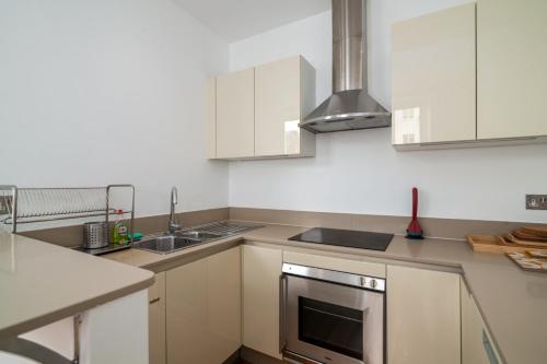 a kitchen with white cabinets and a stainless steel oven at GuestReady - Chic flat in the heart of Kensington in London