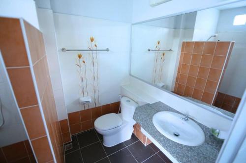 W łazience znajduje się umywalka, toaleta i lustro. w obiekcie Siya House Hotel w mieście Chiang Rai