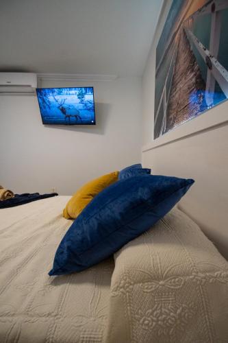 a bed with a blue pillow and a tv on a wall at SUMMERLAND SUNSET in Los Cristianos