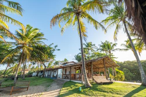 ein Haus am Strand mit Palmen in der Unterkunft Pousada da Barra Caraíva in Caraíva