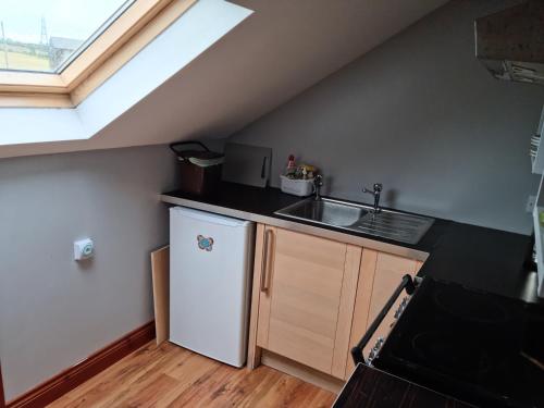 una pequeña cocina con fregadero y nevera. en Cute loft apartment sleeps 4 en Antrim