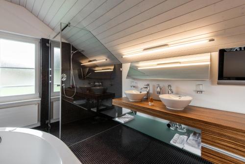 a bathroom with two sinks and a tv on the wall at Hotel Thorenberg in Lucerne