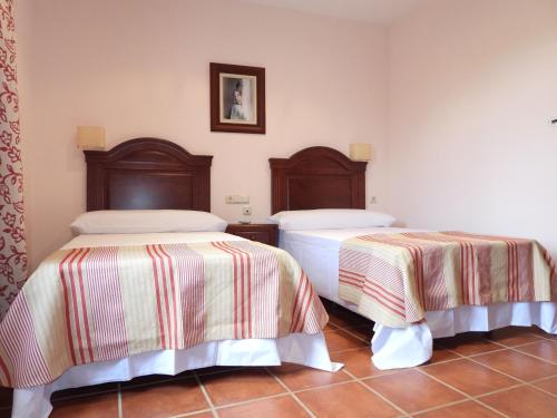 a bedroom with two beds with striped sheets at Hotel Rural Carlos Astorga in Archidona