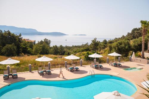 a swimming pool with chairs and umbrellas and the ocean at Naftilos in Pythagoreio