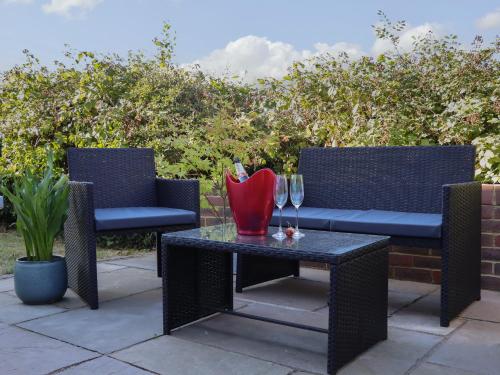 a patio with two chairs and a table with wine glasses at Albies End in Battle