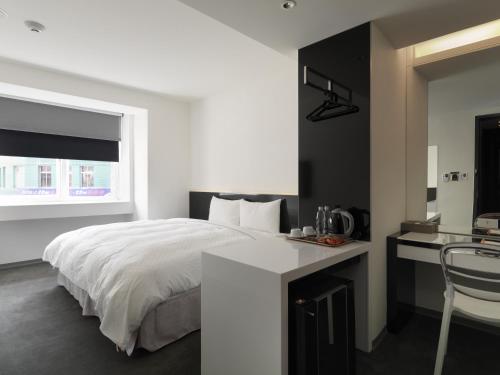 a bedroom with a bed and a desk and a window at CityInn Hotel Plus - Taichung Station Branch in Taichung