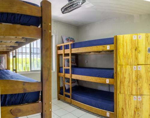 Habitación con 3 literas y sábanas azules. en Aloha Hostel Pinhões, en Fortaleza