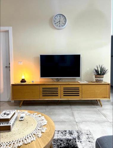 a living room with a television on a wooden cabinet at נופש נחל קורן in Hagoshrim