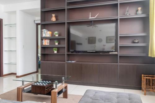 a living room with a large entertainment wall with a television at Lujoso condominio con lavadora y secadora, S. José in San José