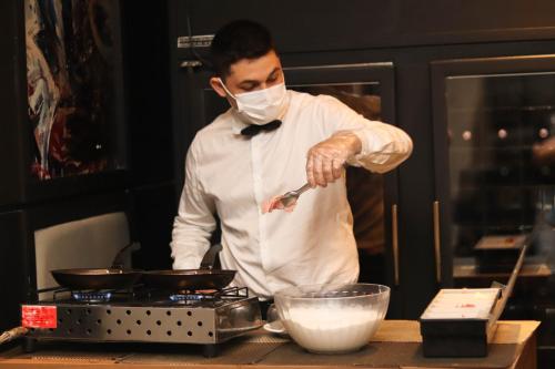 a man in a mask preparing food in a kitchen at Manaus Hotéis Millennium in Manaus
