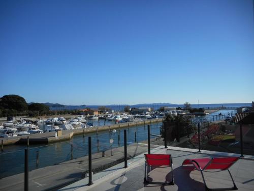 two red chairs sitting on a balcony overlooking a marina at SUPERBE VILLA VUE MER JUSQU'A 14 COUCHAGES La LONDE LES MAURES Entre HYERES et Le LAVANDOU 4 Etoiles PISCINE CHAUFFEE in La Londe-les-Maures