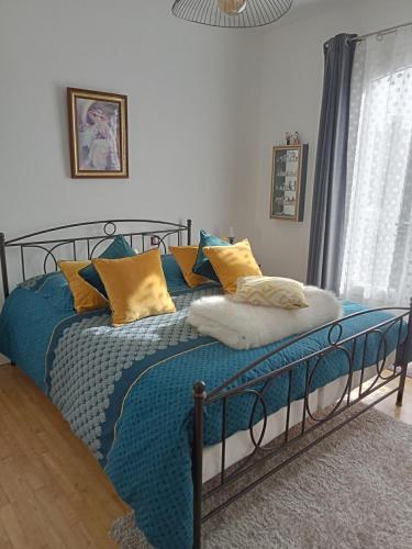1 dormitorio con 1 cama con almohadas azules y amarillas en Chambre privative avec salle d'eau, en Chasseneuil