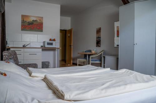 een slaapkamer met 2 witte bedden en een keuken bij Hotel Garni FairSchlafen in Minden