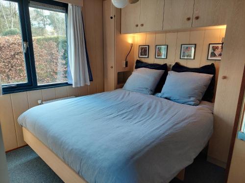 een slaapkamer met een groot bed met blauwe kussens bij Chalet Bosrust in Wolfheze