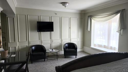 a bedroom with two chairs and a television on a wall at Lowell Inn in Stillwater