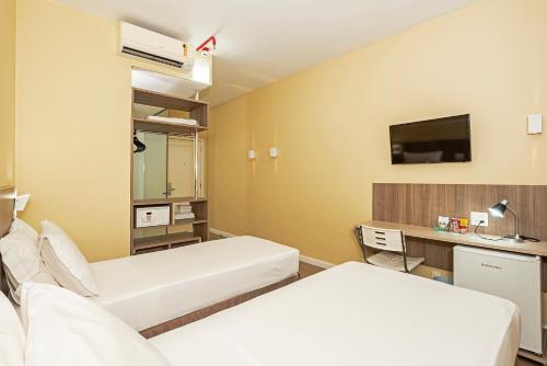 um quarto de hospital com duas camas e uma televisão em Slim Cuiabá Aeroporto by Slaviero Hotéis em Várzea Grande