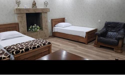 a bedroom with two beds and a chair and a fireplace at Ann Appartment in Tbilisi City