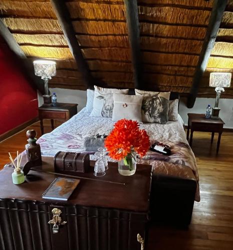a bedroom with a bed and a table with flowers on it at Farm Vibes Guest House in Brits