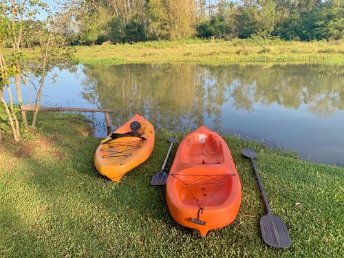 two kayaks sitting on the grass next to a lake at Pousada Equilíbrio dos Canyons in Praia Grande