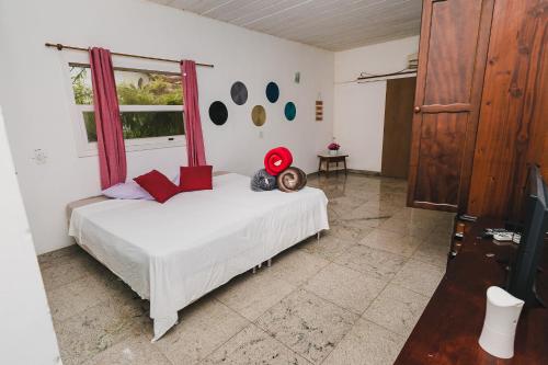 a bedroom with a white bed and a window at Suítes E-Ponto - Entre o Centro Histórico e Mata Atlântica in Paraty