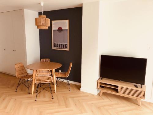 a living room with a table and a flat screen tv at Apartament Family Premium - Baltic Sun Sztutowo in Sztutowo