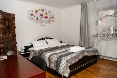1 dormitorio con 1 cama, 1 mesa y 1 jarrón de flores en Apartament Panoramic la casa in comuna Rasinari, en Răşinari