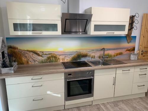 a kitchen with a sink and a painting of a beach at Haus Ole in Kröslin