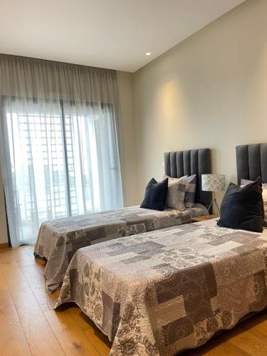 two beds in a room with a window at Luxury Flat in Casa Finance City in Casablanca