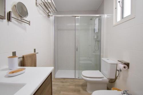 a white bathroom with a shower and a toilet at Casa Los Titos in Arriate