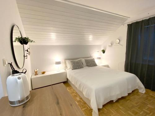 a white bedroom with a white bed and a mirror at Studio Tara with balcony in Bled