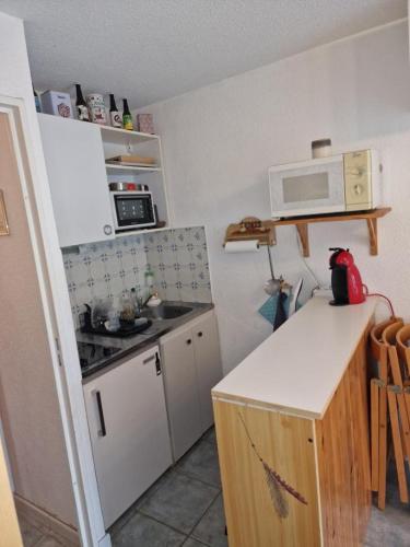 une petite cuisine avec une cuisinière et un micro-ondes dans l'établissement Résidence les étoiles, à La Foux