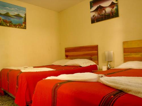 2 camas en una habitación con sábanas rojas. en Hospedaje Eli Panajachel, en Panajachel