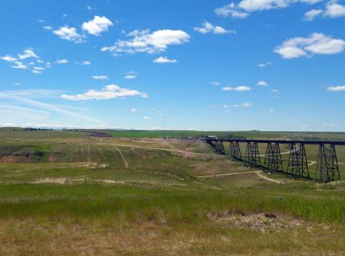 a train crossing a bridge in a field at Super 8 by Wyndham Cut Bank in Cut Bank