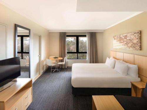 悉尼Mercure Sydney Macquarie Park的配有床和电视的酒店房间