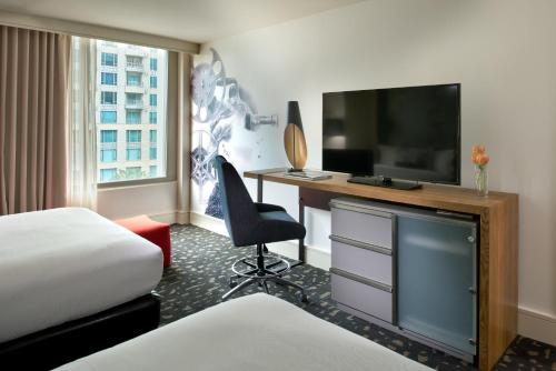 a hotel room with a desk with a television and a bed at Kimpton Hotel Palomar Los Angeles Beverly Hills, an IHG Hotel in Los Angeles