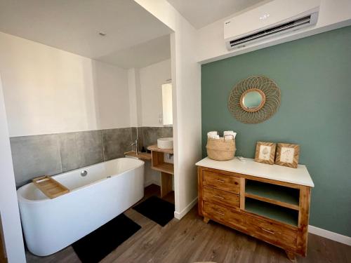 ein Badezimmer mit einer Badewanne, einem Waschbecken und einem Spiegel in der Unterkunft Très bel appartement central, au calme avec balnéo in Perpignan