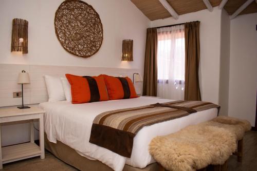 a bedroom with a bed with orange pillows and a window at NOI Casa Atacama in San Pedro de Atacama