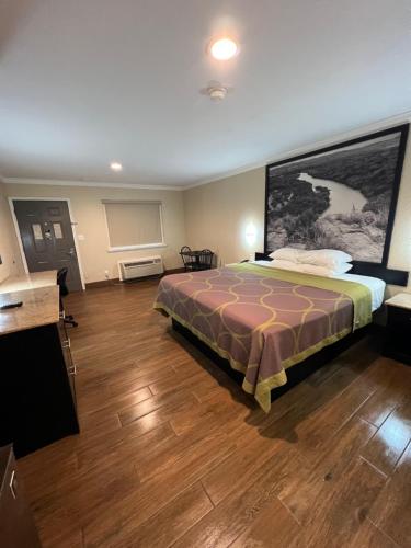 a bedroom with a bed with a large painting on the wall at Super 8 by Wyndham McAllen-Downtown-Airport-LA Plaza Mall in McAllen