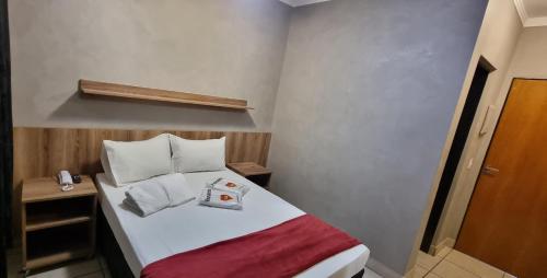 una piccola camera con un letto con una coperta rossa di Hotel Pousadas Club a Sorocaba