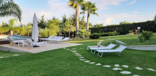 une pelouse avec des chaises longues et une piscine dans l'établissement Isola del sole, Appartamenti con piscina, à Balestrate