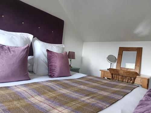 1 dormitorio con 1 cama con almohadas moradas y blancas en Keepers Retreat, en Rowlands Castle