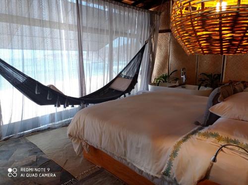 a hammock in a bedroom with a bed and a window at Hotel Bendita Luna Salchi in Cuatunalco