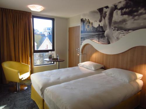 a hotel room with two beds and a large window at ibis Styles Saint Malo Port in Saint Malo